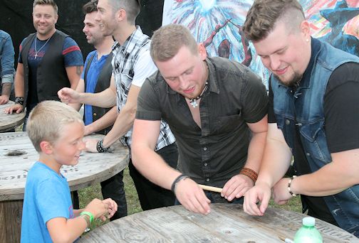 Brian Hummel (L), 8, of Shallow Lake gets the Cold Creek County band to sign his drum stick; signing, are Josh Lester and Justin Lester of the band; photo by David Dadson